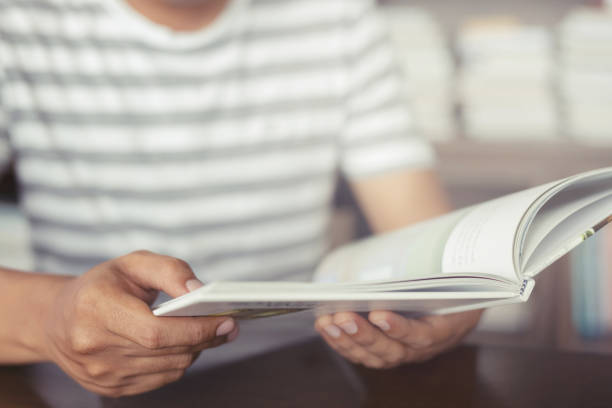 istock close up student young man hand holding books are placed front bookshelf in a library University. love to read education concept. with filter Tones retro vintage warm effect. 1057149828