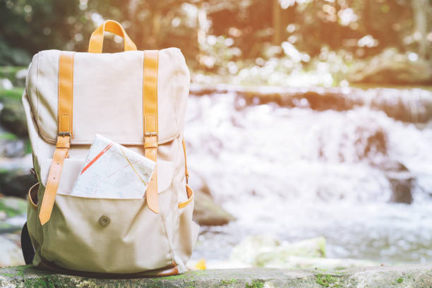 istock Hipster Backpack walk in the forest Travel accessories and map on Timber lumber log. View from backside tourist traveler bag on background Forest tree. concept holidays Travel. 1057149872