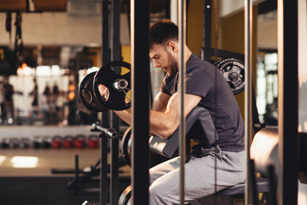 istock Handsome man doing biceps lifting barbell on bench in a gym 1057152164