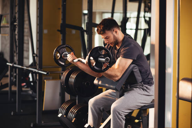istock Handsome man doing biceps lifting barbell on bench in a gym 1057152172