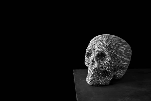 closeup of a sparkly skull on a dark gray surface, against a black background, with some blank space on the left