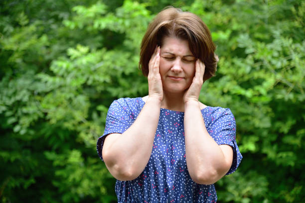 istock woman holds her hands to her temples 1057163534