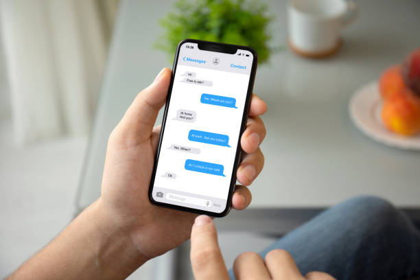 main de l’homme tenant téléphone avec messenger application sur l’écran - text photos et images de collection