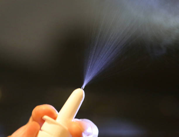 Mist from a nasal spray pump Person's fingers pressing on a white nasal spray pump with mist being sprayed from the nozzle nasal spray stock pictures, royalty-free photos & images