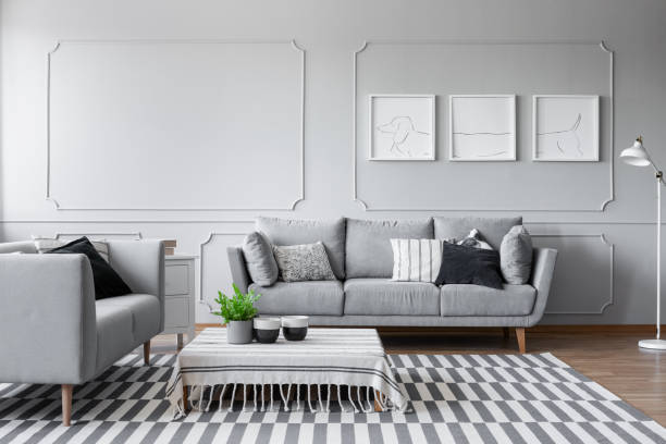 istock Elegant living room with two comfortable grey sofas with pillows and graphic on the wall, real photo with copy space and mockup 1057173798