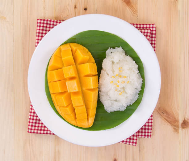 istock Mango sticky rice. Thai style dessert, mango with glutinous rice on red folded tablecloth on wooden table background. 1057184022