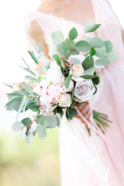 istock bride's hands hold beautiful bridal bouquet outdoor 1057186516