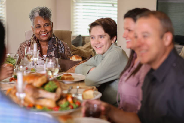 istock Diverse family at dining table eating Thanksgiving dinner. 1057189272