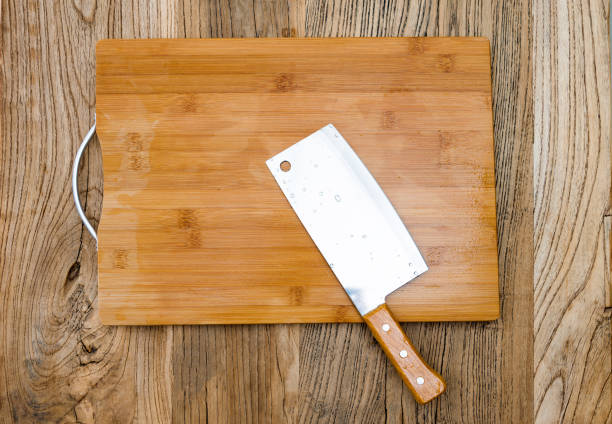 Knife and cutting board on wooden table.