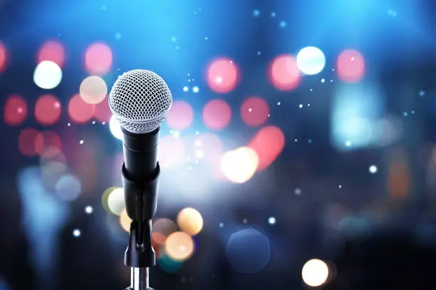 Close up of microphone setting on stand with colorful light bokeh background in concert hall ,showbiz concept.