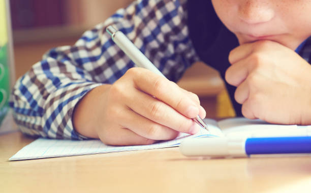 istock Caucasian little boy holding pen and writing in notebook. Close up. 1057194832