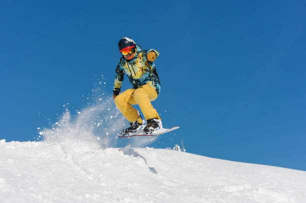 istock Young active snowboarder in bright sportswear jumping up on a mountain slope 1057195054