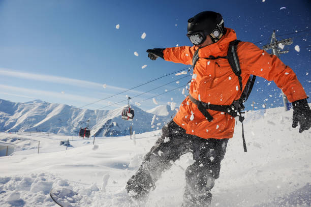 snowboarder profesional naranja ropa deportiva por una ladera de la montaña del montar a caballo - snowboarding extreme sports action snowboard fotografías e imágenes de stock