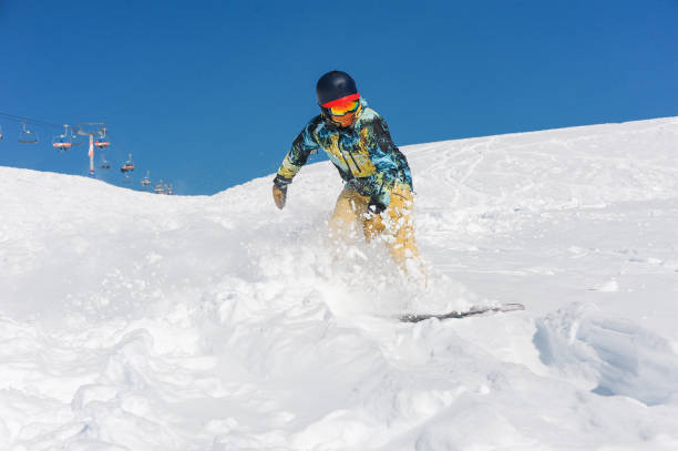 istock Professional active snowboarder in bright sportswear riding down a mountain slope 1057197682