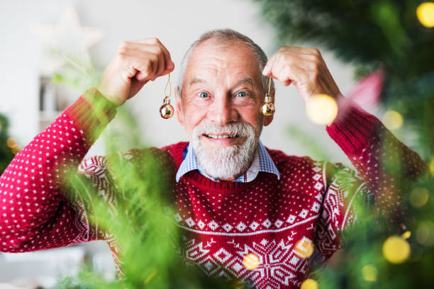 istock A senior man standing by Christmas tree, holding balls ornaments. 1057205190