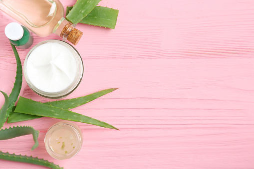 skin cream and aloe vera on a pink wooden table