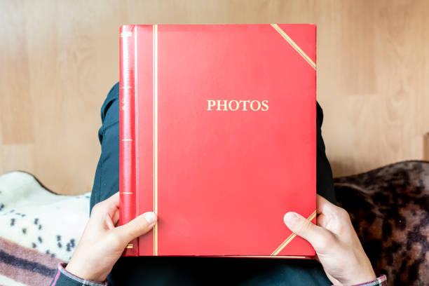 hände halten hautnah und öffnen sie rote familienfoto album zu hause sitzen, vorbei an speicher konzept f - family album stock-fotos und bilder