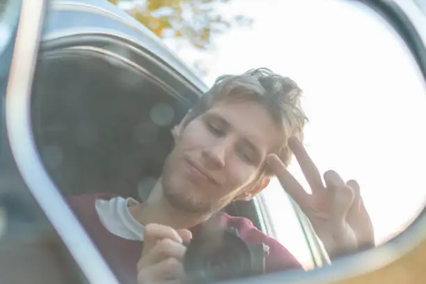 Photo of young driver taking a self portrait with professional camera in the car window  f