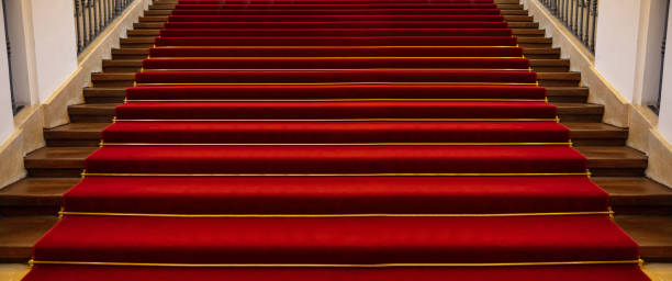 istock Wooden staircase covered with red carpet background 1057235164