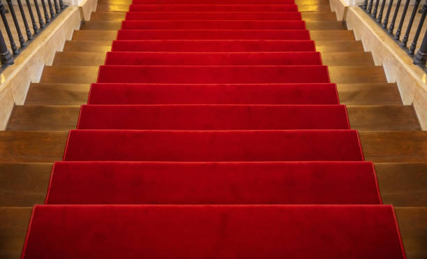 istock Wooden staircase covered with red carpet background 1057235174