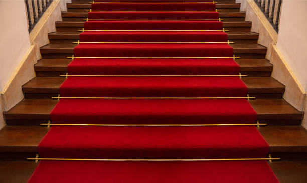 istock Wooden staircase covered with red carpet background 1057235180