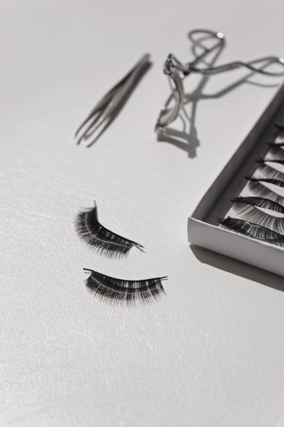 istock Black false lashes strips set with curler and tweezers on white background 1057235620
