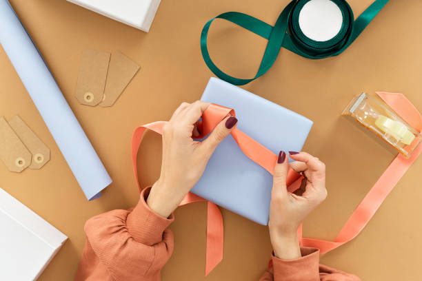 istock holiday gift packaging. woman packaging boxes on brown background 1057240388