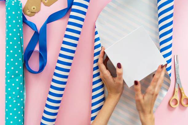 istock holiday gift packaging. woman packaging boxes on pink background 1057240592