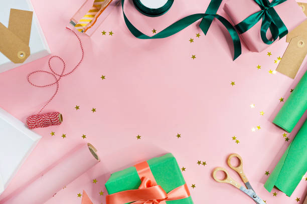 istock holiday gift packaging. woman packaging boxes on pink background 1057240670