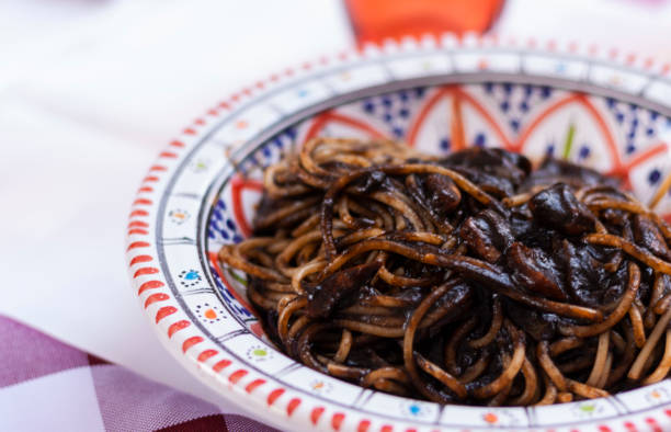 istock Black squid ink pasta on the plate with red-blue pattern 1057246032