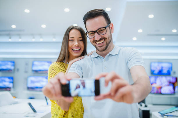 istock Couple making selfie in tech store. In bacground TV screens. 1057248518