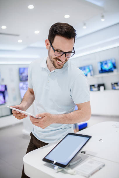istock Happy man choosing which tablet to buy. Tech store interior. 1057248698