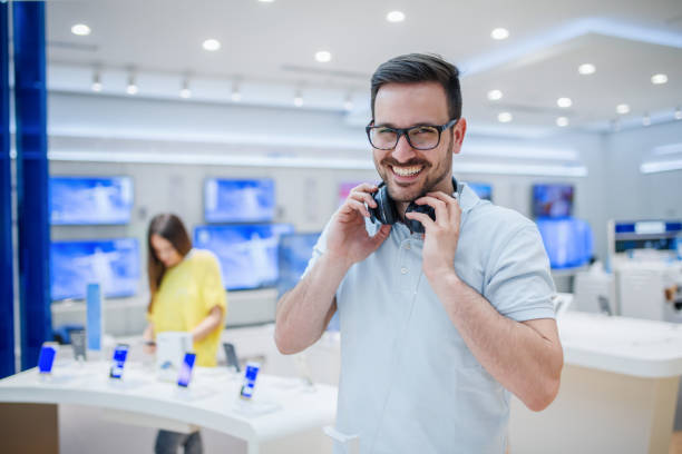 Happy man posing with earphones in tech store. Technology shopping concept. Happy man posing with earphones in tech store. Technology shopping concept. sound technician stock pictures, royalty-free photos & images