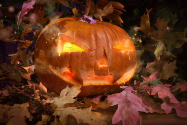 istock Halloween pumpkin outdoors with candle inside and oak leaves 1057248762
