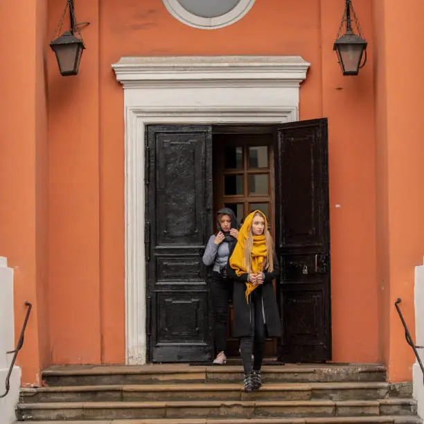Two women come out of the door and go down the steps of a historic building.