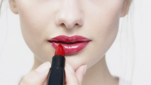 Portrait of beautiful woman applying red lipstick