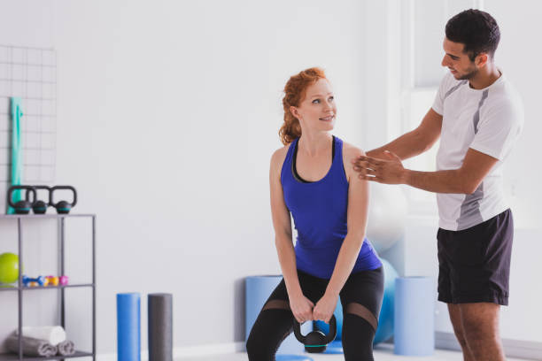 istock Personal trainer giving instructions to his client who it with is working out with a kettle bell 1057265138