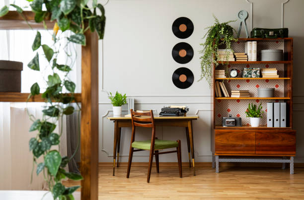 noir retro machine à écrire sur un bureau en bois unique, une chaise moderne du milieu du siècle et une bibliothèque rénovée dans un décor de bureau à la maison de hipster. vraie photo. - furniture photos et images de collection