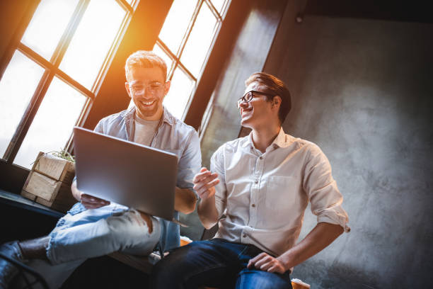 due colleghi di lavoro seduti a un tavolo, che hanno una riunione. - office style foto e immagini stock