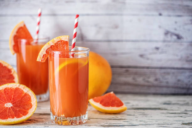istock Fresh grapefruits and two glasses of grapefruit juice on light wooden table. With copy space 1057288732
