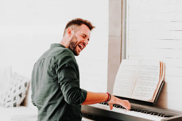 istock Young man playing electric piano at home 1057297164