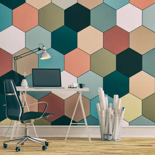 Workdesk with decoration on hardwood floor in front of multicolored hexagon tiled wall with copy space. 3D rendered image.