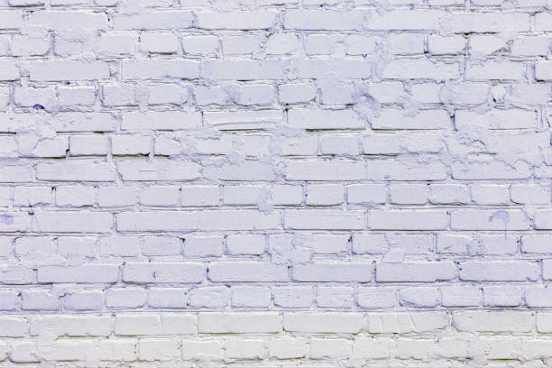 istock Brick wall painted with light lilac paint. Background with brickwork texture. 1057304238