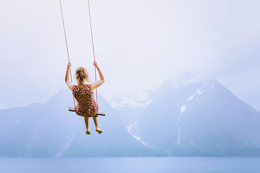 happiness concept, happy girl child on the swing on beautiful mountain landscape