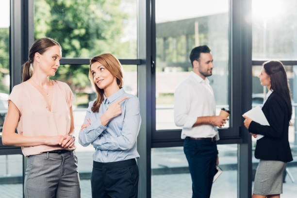 istock businesswomen gossiping while collegaues having conversation behind in office 1057325512