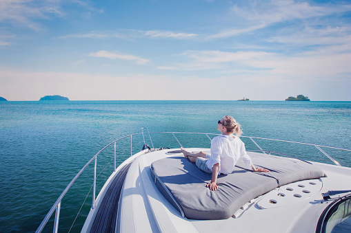 Young Woman enjoying sailing on a blue sea, sunbathing on a boat deck. Pretty woman relaxing on a yacht Copy space