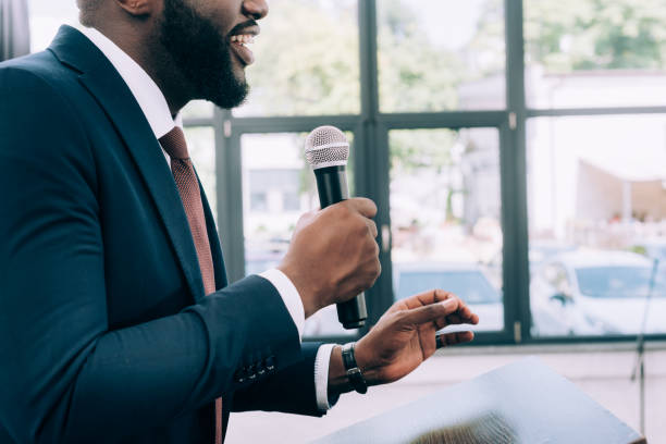 istock cropped image of smiling african american speaker talking into microphone during seminar in conference hall 1057329940