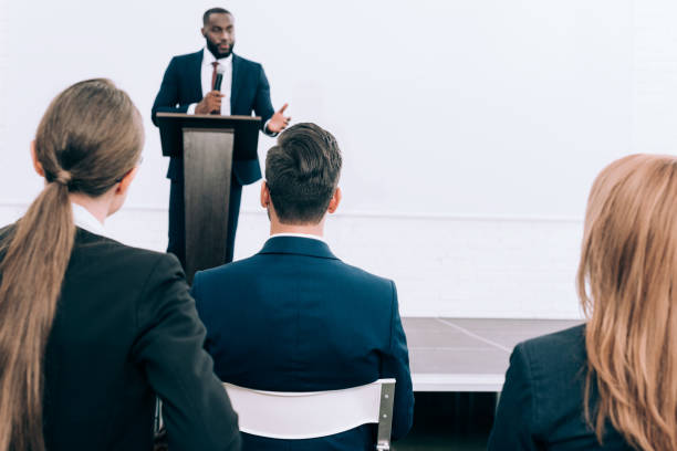 istock handsome african american speaker talking in front of audience conference hall 1057330046
