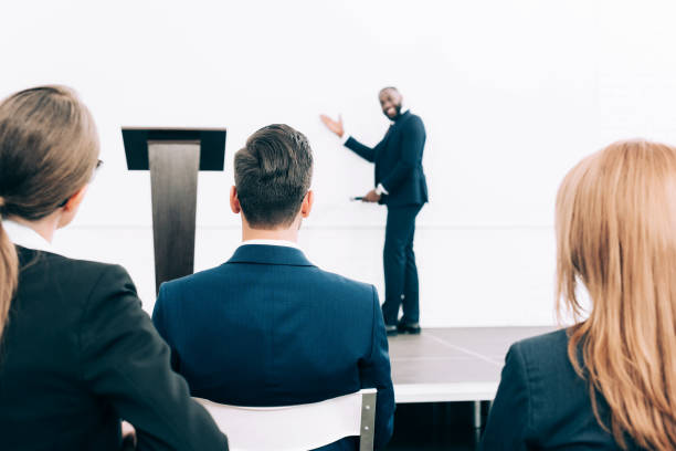 istock selective focus of smiling african american speaker pointing on screen in conference hall 1057330054