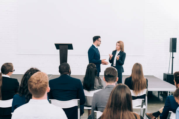 istock colleagues talking in front of multicultural audience during seminar in conference hall 1057330086